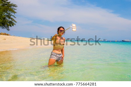 young beautiful and happy Asian Chinese woman having fun on sea water taking selfie picture with mobile phone camera on paradise beach water smiling in holiday and vacation concept