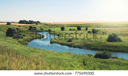 Sunny summer landscape with river.Green hills and meadows. 