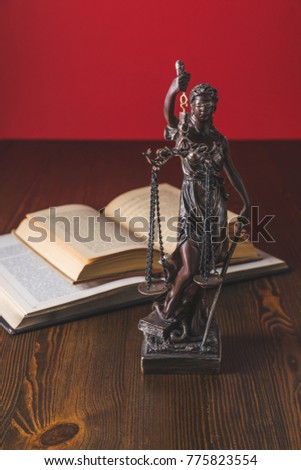 opened juridical books with lady justice statue on wooden table, law concept