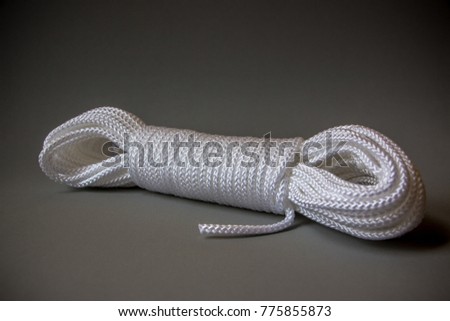Coiled white Nylon Rope on gray background. Isolated closeup photo. This Nylon rope is a general-purpose rope with can uses in the home, garden, agriculture, building, and many other general uses. Royalty-Free Stock Photo #775855873