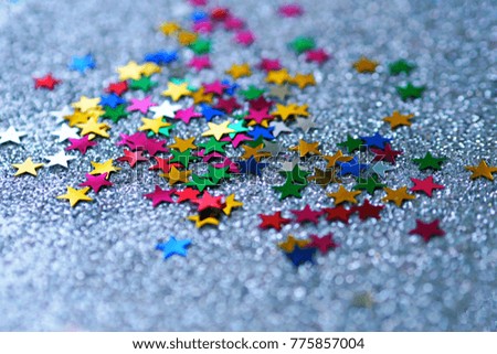Colorful stars glittering on silver glitter texture background top view closeup