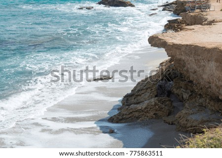 The waves breaking on a stony beach, forming a spray. Wave and splashes on beach.