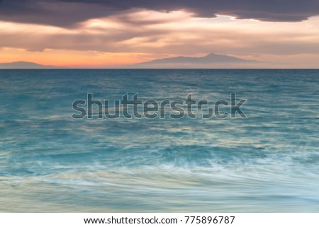 Crimson sunset on the shore of the orange calm sea In the Greece