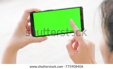 woman take cell phone with green screen in the home
