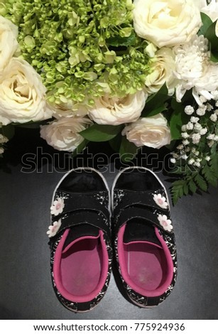 Kids shoes toward flower bouquet full of white roses