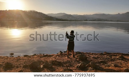 a man taking a picture of the landscape against the sea 