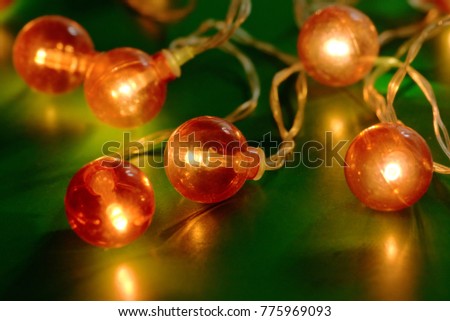 Electric garland with red light bulbs on a green background.