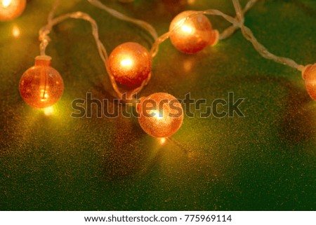 Electric garland with red light bulbs covered with frost on a green background.