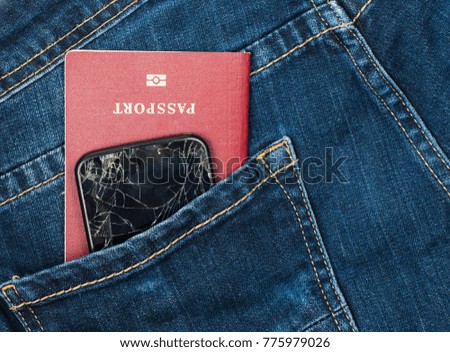Mobile phone with broken screen and passport in jeans pocket.