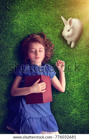 Little girl sleeping with a book on grass