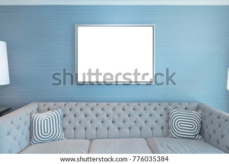 Blank picture frame on a blue wall above a stylist couch
