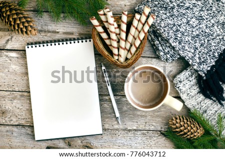 notebook, blank sheet of paper, mug, coffee, scarf, cookies on a wooden table
