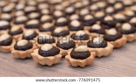 Coconut cupcakes with chocolate filling and almond garnish. Decorative sweet Christmas pastry stacked on a wood background. Small depth of sharpness.