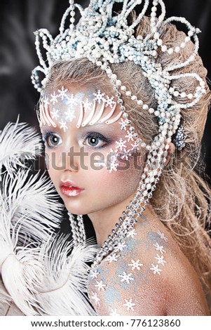 close up portrait of beautiful girl. professional winter makeup. hair in snow. snow princess with white fan