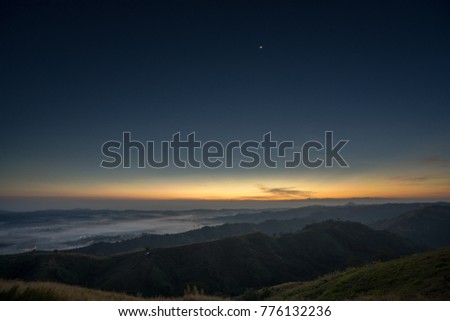 First light before sunrise on the misty mountain covered city below.