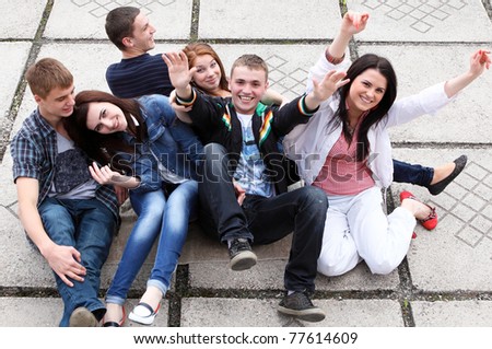 Group of male and female students sitting on street