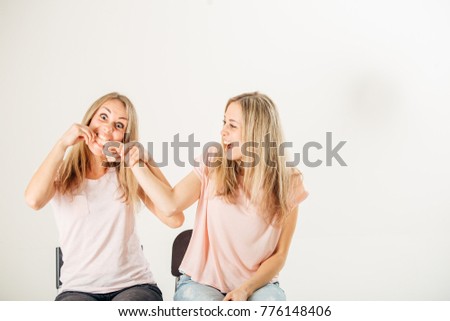 closeup portrait picture of woman biting finger of her sister.