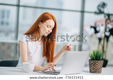 Close up of a happy redhead woman hand buying online with a laptop and paying with a credit card