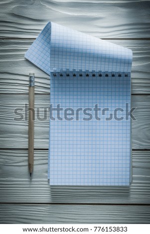 Checked notepad pencil on white wooden board.