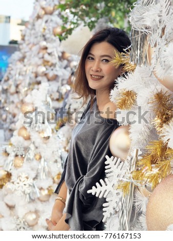 Portrait of beautiful Asian woman with white Christmas tree decorated of golden and silver ornaments