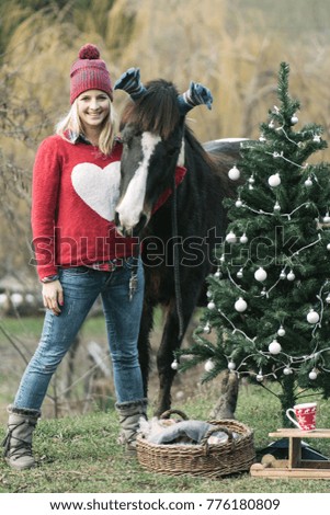 Christmas image. Funny image of woman and her horse waiting for Christmas magic. Christmas tree and decoration outdoor. 