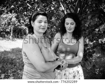 Two mature american woman friends speaking in park about life. Black and white vintage style photo