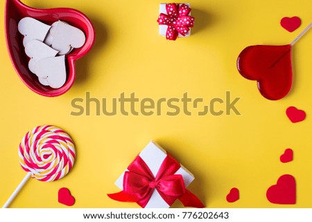 Valentine's day bright yellow background, greeting card concept,  lollipop or sweet candy on sticks, with gift box, decorative hearts. copy space