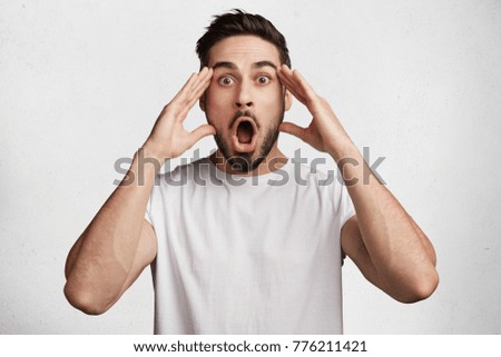 Horizontal shot of stupefied stunned shocked bearded young male keeps mouth widely opened, being surprised and very emotional as forgets about important meeting, expresses great surprisment. Royalty-Free Stock Photo #776211421
