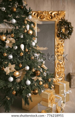 Closeup of Christmas tree decoration with wreath on golden frame mirror leaning on wall