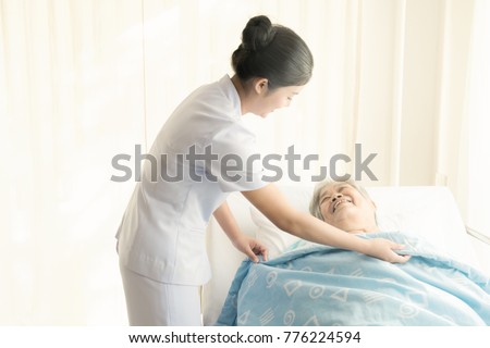 Nurse with patient. Routine health check and putting elderly patient to bed. Female nurse with senior chinese woman. Royalty-Free Stock Photo #776224594