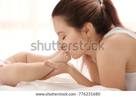 Mother kissing her baby's feet at home