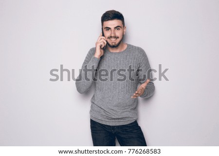 Bearded man talking on Phone and Smiling. Picture of young man talking on the phone and smiling. Looking at camera.