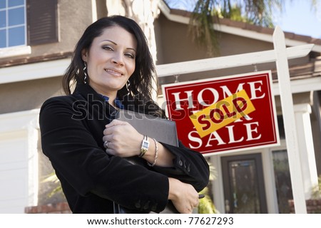 Proud, Attractive Hispanic Woman in Front of Sold Real Estate Sign and New Home.
