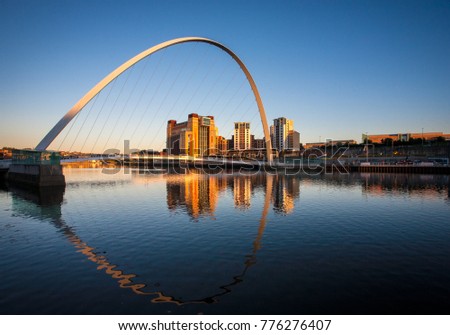 Millenium Bridge on Newcastle Quayside illuminated by the evening sun and reflected in the river Tyne Royalty-Free Stock Photo #776276407