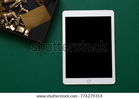 Mockup image of tablet and box with blank gift card on green table. Online shopping voucher, blank screen mock up, copy space top view