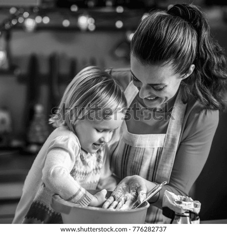 Mother and baby playing while making christmas cookies in kitchen