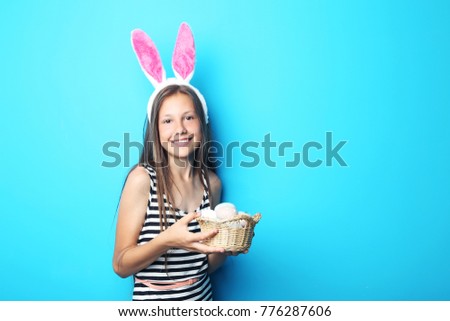 Portrait of beautiful girl with eggs in basket on blue background