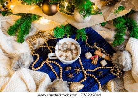 Hot chocolate with marshmallows, cinnamon and anise in Christmas setup with tree and decorations
