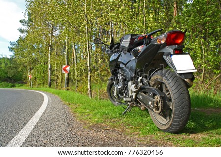 black motorbike standing on roadside