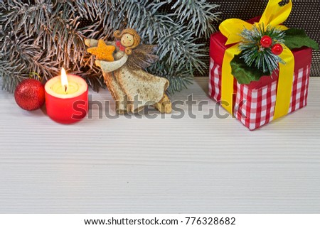Christmas gift, candle, decorations,  spruce branches lie on a white table. Back background broun. Color photo.