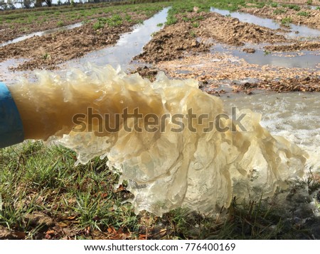 water flows from a pipe or water gushing out of the pipe close up from large pump tube in rice field in central Royalty-Free Stock Photo #776400169