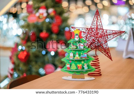 Red star & Christmas tree paper craft decoration on the wood table with blur big Christmas tree behide.