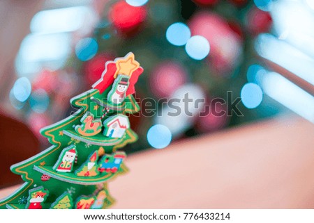 Christmas tree paper craft decoration on the wood table with blur big Christmas tree behide.