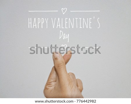 Hand doing mini heart shaped hand. (South korea's style to say I love you) on white background, and Happy Valentine's day wording with heart drawing on the picture.