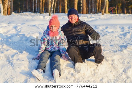 Dad with daughter have a rest on the edge of the rink