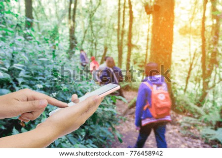 Man use mobile phone, blur image of tourists hiking as background.