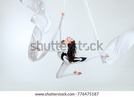 Aerial artistic acrobatics, a woman demonstrates poses. Royalty-Free Stock Photo #776475187