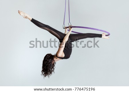 Woman aerial acrobat on the ring shows tricky tricks. Royalty-Free Stock Photo #776475196
