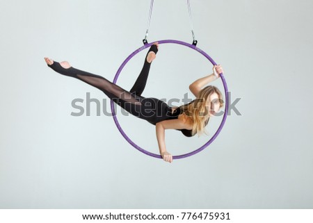 Woman aerial acrobat performs with tricks on the hula hoop at the top. Royalty-Free Stock Photo #776475931