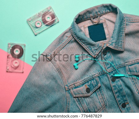 Audio cassettes, headphones and jeans jacket on a blue pink creamy background. Entertainment and fashion 80s.